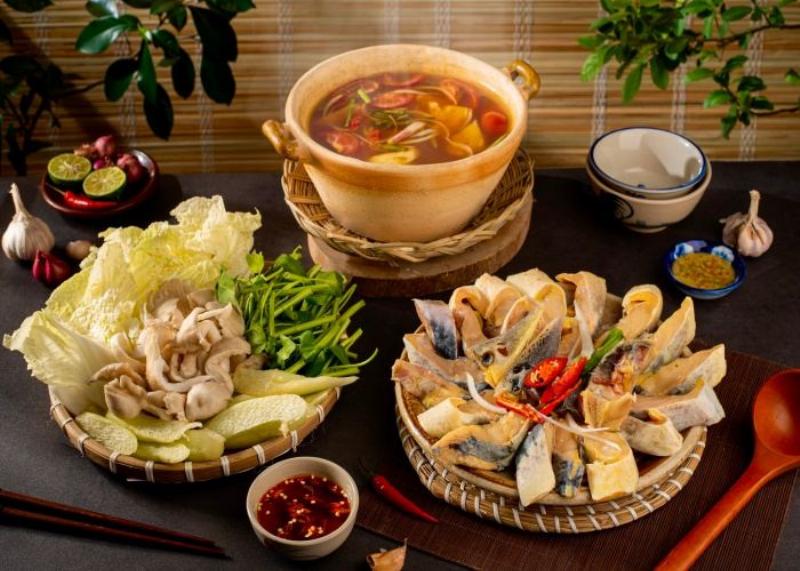 Một bát lẩu cá tầm đầy đặn có cá, rau và bún hoặc mì